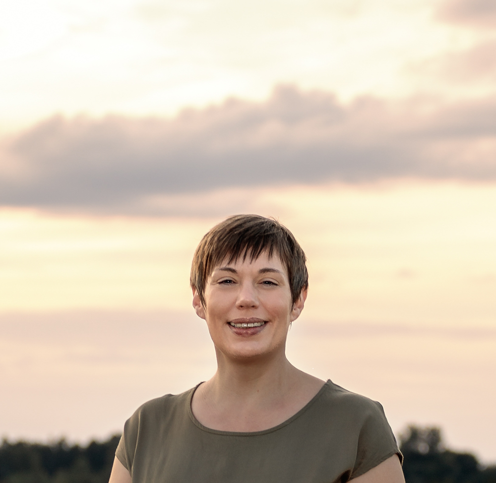 Dorothee Hildbrand, Hypnose Coach in Nagold, lächelt entspannt im Abendlicht vor ruhigem Himmel – ein ruhiges Portrait, das innere Ruhe und Klarheit ausstrahlt.